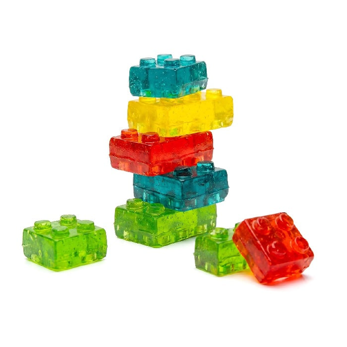 A stack of translucent, colorful toy building-block-shaped pieces in green, yellow, red, and teal, arranged on a plain white background.