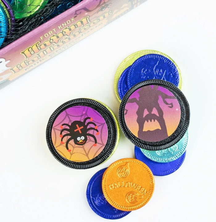 Halloween-themed Oreo-style chocolate cookies with colorful printed designs, including a spider on one cookie and a haunted house on another, arranged on a white surface with part of the product box visible in the background.